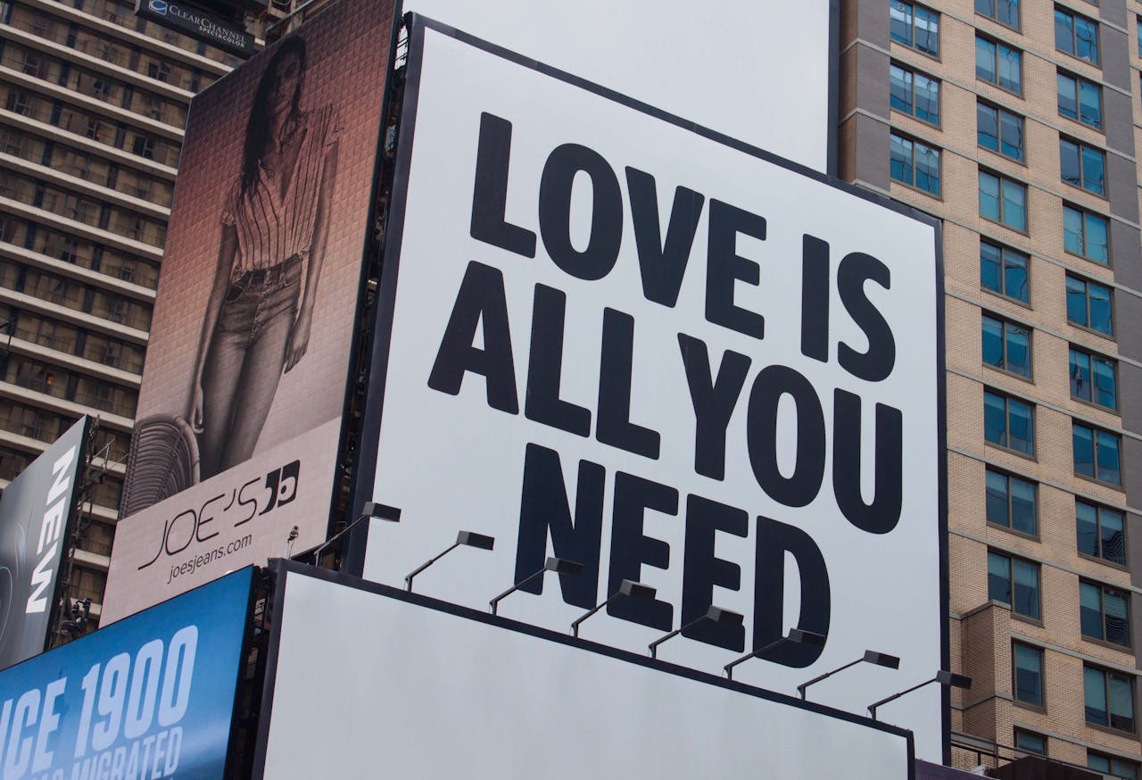 services-02 Large city billboard reads Love Is All You Need in New York City street.